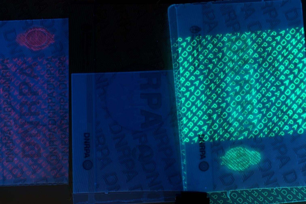 An ID card under a UV light revealing a hidden fluorescent logo